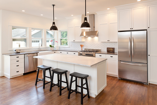 Modern renovated kitchen with white cabinets, stainless steel appliances, and a large center island